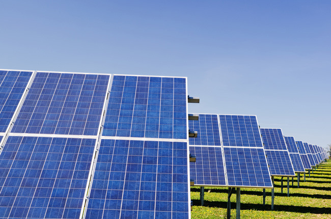 Row of solar panels on a leased solar farm with blue sky above